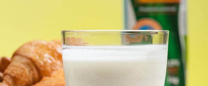 Čaša balans jogurta na stočiću pored kroasana