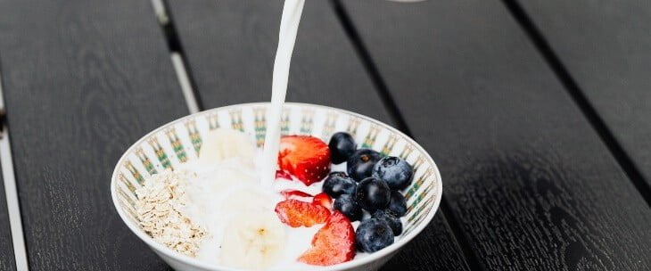 Žitarice i voće u tanjiru koji se prelivaju jogurtom